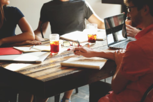 People sit around a table with laptops and beer.